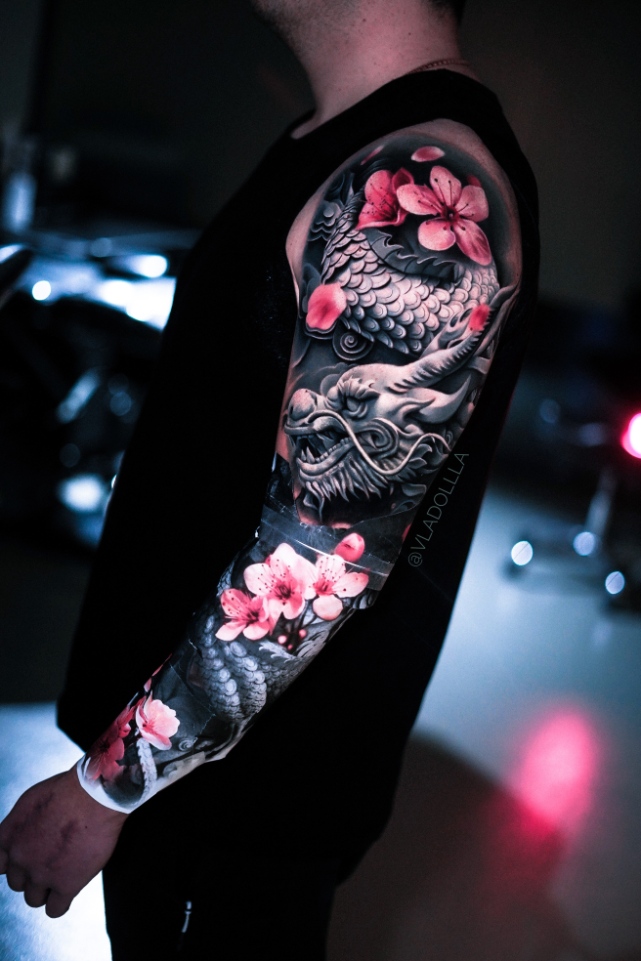 Drachen-Motiv mit Blüten als Teil eines Armtattoos