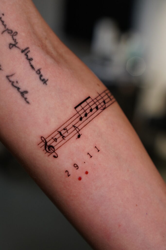 Fineline Tattoo von Musiknoten auf dem Unterarm Fineline Tattoo von Musiknoten auf dem Unterarm